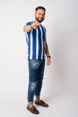 Fototapeta premium Full body shot of happy young bearded Indian man pointing at camera