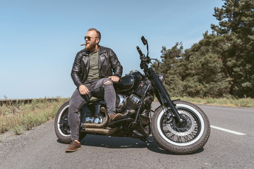 Fototapeta na wymiar Full length of a sexy brutal man posing on his motorcycle