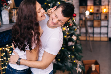 guy and girl in white t-shirts have fun near the Christmas tree