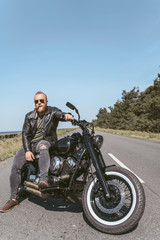 Fototapeta na wymiar Sexy bearded man in leather jacket sitting on his bike