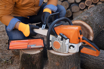 Sharpening a chainsaw Close up on a man sharpening a chainsaw chain with file.