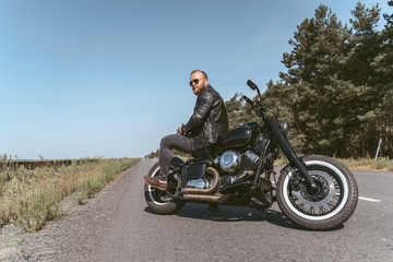 Obraz premium Handsome bearded man sitting backwards on the bike posing