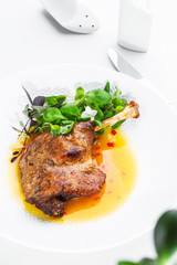 Roast duck leg with mango sauce, salade and chilli pepper on white plate, closeup. Vertical view from above, top shot. White background.