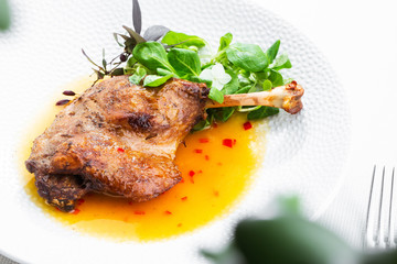 Roast duck leg with mango sauce, salade and chilli pepper on white plate, closeup. Horizontal view from above, top shot. White background.
