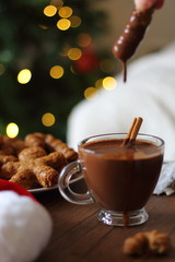 Cup of hot chocolate with gingerbread on wooden table. Christmas background.
