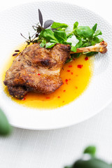 Roast duck leg with mango sauce, salade and chilli pepper on white plate, closeup. Vertical view from above, top shot. White background.