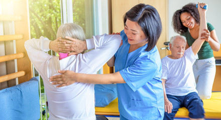 Fototapeta premium Senior retired elderly people in sports clothing in gym, working out with the help of trainer