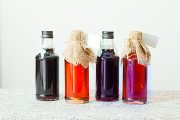 Tasty homemade berries syrup in bottles, on a white shelf