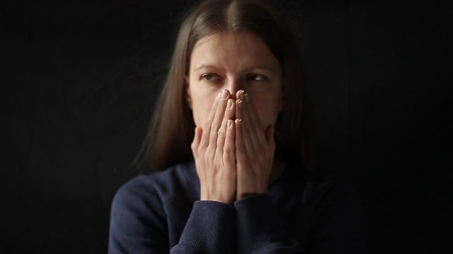 Portrait of a sad young woman on a black background. Depressed state in a girl. 