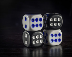 On the wooden surface lie cubes of bone to play white with blue and black with white on a dark background
