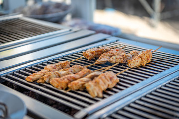 Grilling chicken skewers and hamburgers on a barbecue in a restaurant