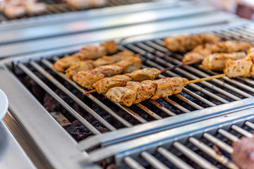 Grilling chicken skewers and hamburgers on a barbecue in a restaurant