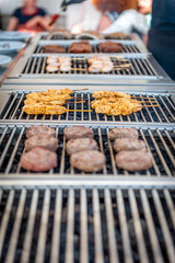 Grilling chicken skewers and hamburgers on a barbecue in a restaurant
