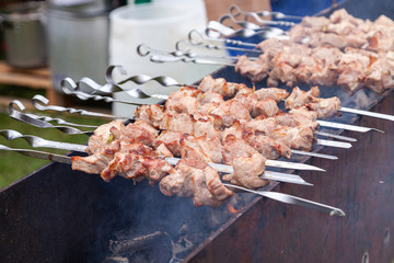 Grilled kebab cooking on metal skewer. Roasted meat cooked at barbecue. BBQ fresh beef meat chop slices. Traditional eastern dish, shish kebab. Grill on charcoal and flame, picnic, street food