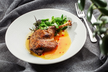 Roast duck leg with mango sauce, salade and chilli pepper on white plate, closeup. Horizontal view from above, top shot. Gray background.