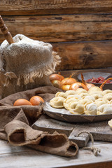uncooked meat dumplings - russian pelmeni on cutting board and ingredients for homemade pelmeni on wooden table. Process of making pelmeni, ravioli or dumplings with meat