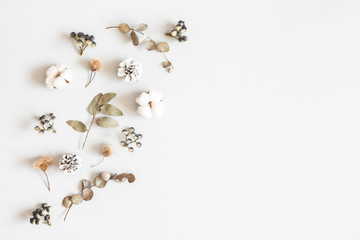 Winter composition. Dried leaves, cotton flowers, berries, pine cones on gray background. Autumn, fall, winter concept. Flat lay, top view, copy space