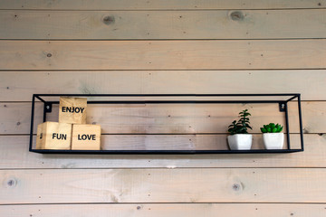 minimalistic rack on wooden wall with decoration for modern home, little green plants closeup