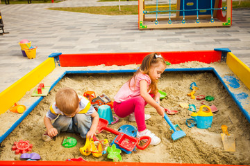 Fototapeta na wymiar Two children playing in sandbox in sunny day