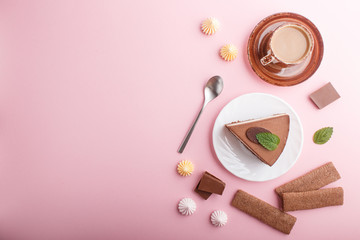 Cake with souffle milk chocolate cream with cup of coffee, meringues on a pink pastel background. top view, copy space.