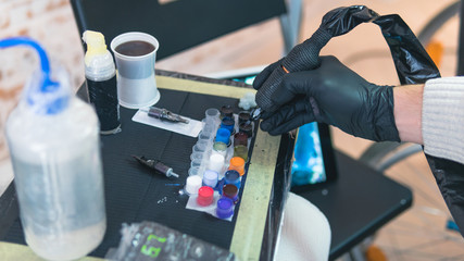 Close-up of tattoo artist work place parts and paint, machines and other equipment. Professional tattooist working tattooing in studio.