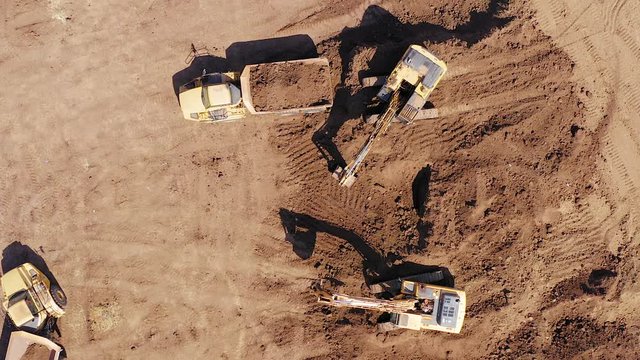 Excavators loading soil onto an Articulated hauler Trucks, Top down aerial image.
