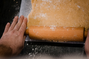 baker's hands roll ginger dough on a dark background. Close-up, soft focus. Side view, top view. Copy space.