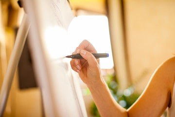 Female writes something with a marker on white board.