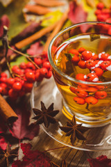 Hot tea in glass cup with rowan and atmospheric autumn decorations. Selective focus. Shallow depth of field.