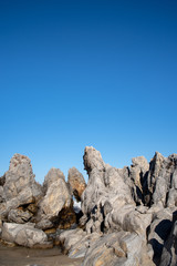 A cloudless blue sky and sea rocks of various shapes.