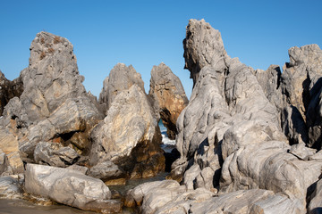 Fototapeta na wymiar A cloudless blue sky and sea rocks of various shapes.