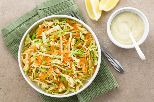 Coleslaw Made Of Freshly Shredded White Cabbage And Grated Carrot With Homemade Mayonnaise-based Salad Dressing And Lemon Wedges On The Side, Photographed Overhead (Selective Focus On The Salad)