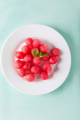 Watermelon balls in a white plate on a turquoise background. Watermelon. Dessert with watermelon