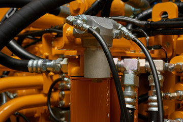 Close up view of hydraulic pipes of heavy industry machine. Low key.