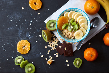 Healthy diet breakfast concept. Oats porridge with banana, kiwi, dark chocolate and citrus