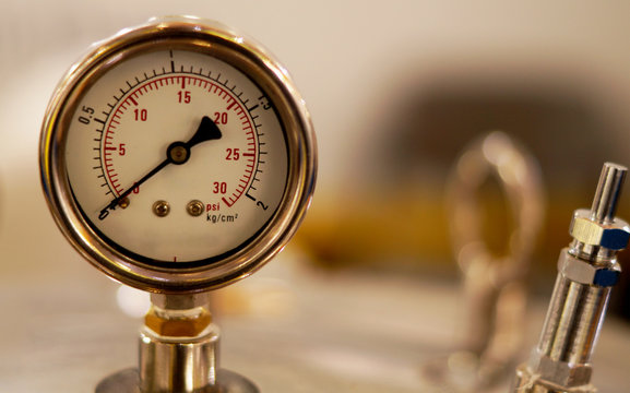 View of analog meter ,steel pipes and industrial process equipment background