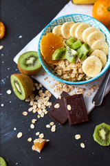Healthy diet breakfast concept. Oats porridge with banana, kiwi, dark chocolate and citrus