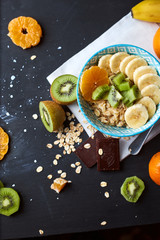 Healthy diet breakfast concept. Oats porridge with banana, kiwi, dark chocolate and citrus
