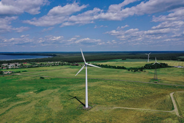 Fototapeta na wymiar Wind turbines of electricity against background of fields and forests. Renewable and environmentally friendly energy concept
