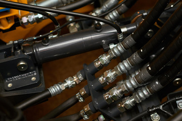 Close up view of hydraulic pipes of heavy industry machine. Low key.
