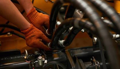 Low key photo of hydraulic pipes maintenance on heavy industry machine.