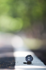Selective focus Stainless steel watches are placed on a white line on a street in a park where nobody, have to blur green background