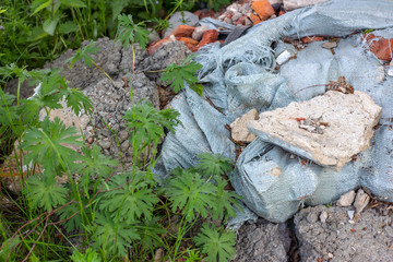 Сonstruction garbage, debris and waste rubble in a remote green area. Nature and soil pollution concept