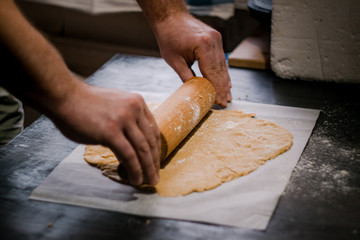 baker's hands roll ginger dough on a dark background. Close-up, soft focus. Side view, top view. Copy space.