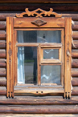 Window with carved platbands in an old wooden house. Front view.