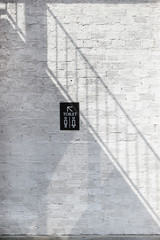 Light and shadow of stairway on the white wall with toilet sign to toilet area.