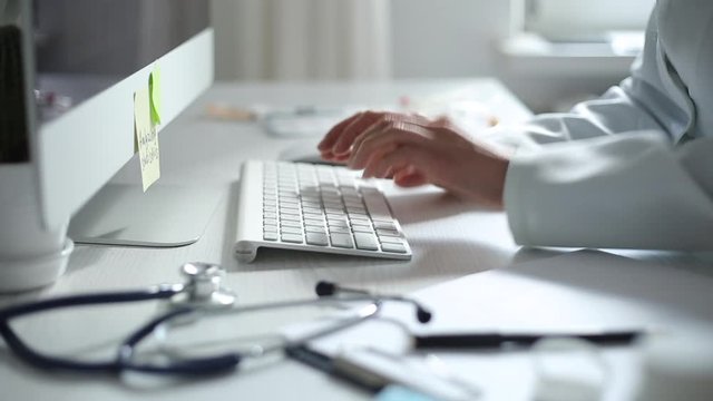 Hands of a doctor working on a computer keyboard. Close-up.