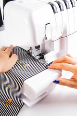 Overlock. The woman sews the knit fabric on the overlock