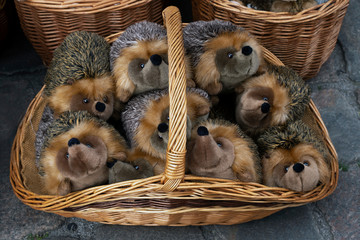 plush hedgehogs in a wicker basket outside. sale of soft toys