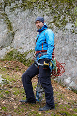 climber in a blue jacket with his equipment on the belt, ready to climb. against mountains. autumn